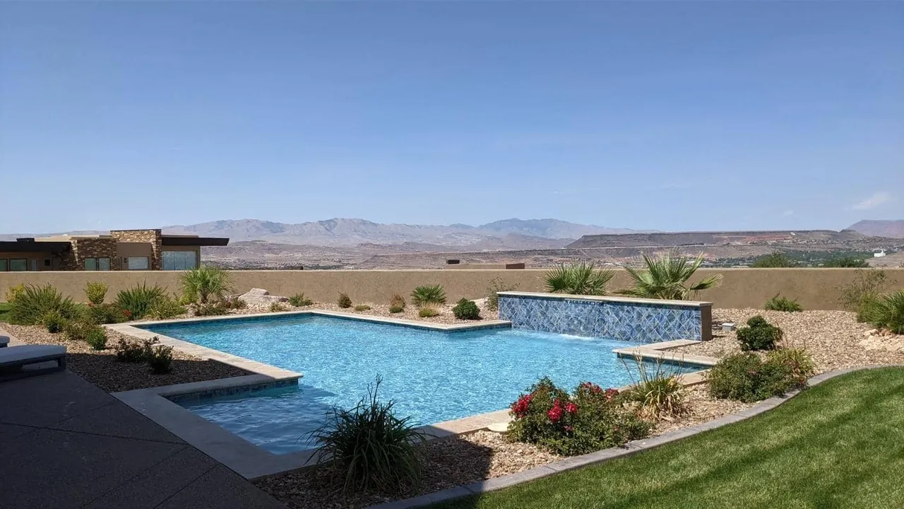 Blue backyard pool with a tiled water-feature wall and desert views