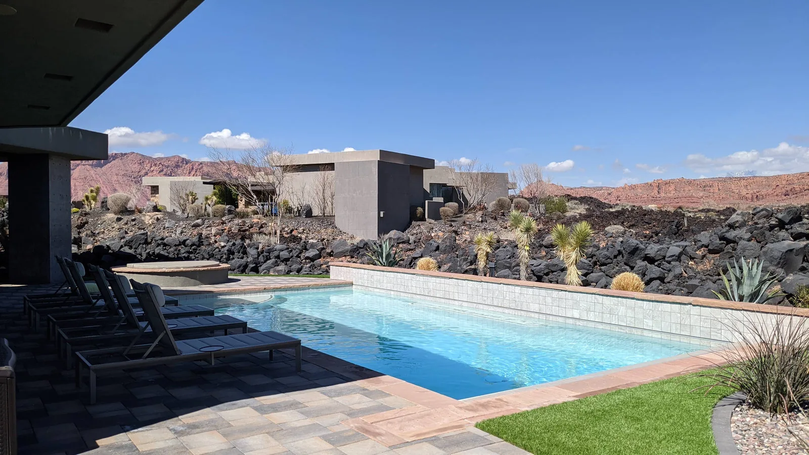 A clear backyard pool framed by Southern Utah red cliffs
